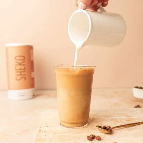 Iced Glow Coffe aus dem Mixer in ein Glas umfüllen. Mit der Milch aufgießen.
